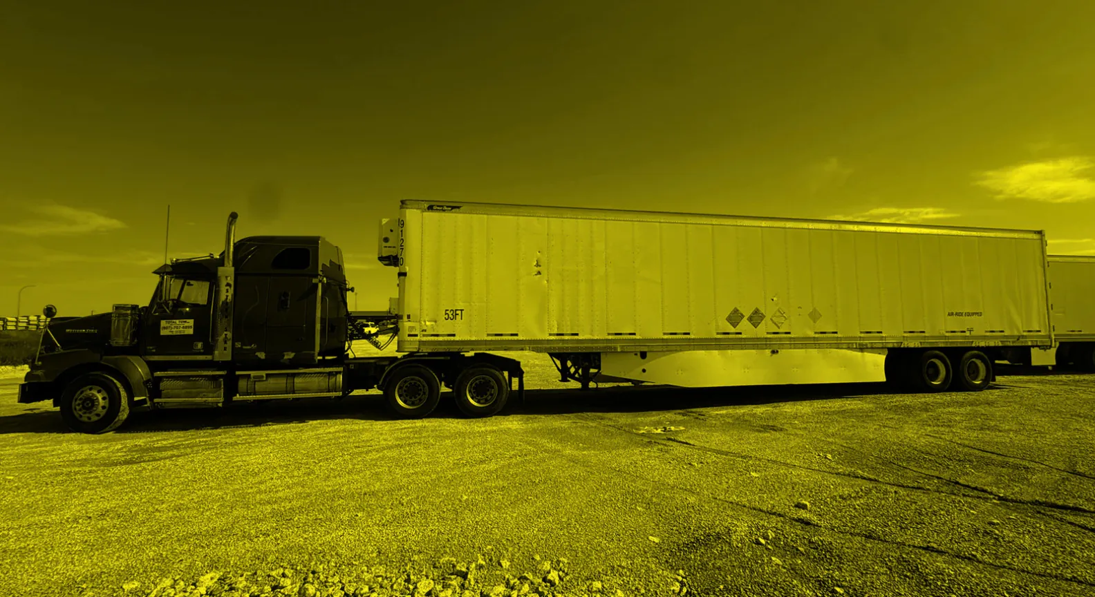 A loaded Total Trucking flatbed truck with a 53ft trailer, hazmat placards visible, Total Tow decal on the door